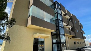 A modern hotel building with a glass facade, a flat roof, and a visible entrance. - Hotel Prime Suítes (Cupira)
