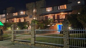 A brick building with multiple windows and a gated entrance. - Pousada Jardim da Lagoa (Garopaba)