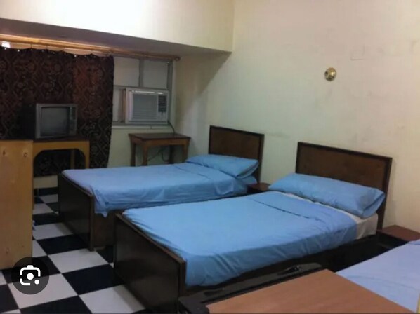 A room with two single beds, a small desk with a chair, a television, and a patterned wall. - Nubian oasis hotel aswan (Aswan)