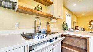 A kitchen with a stainless steel sink, wooden shelves, and white cabinetry. - Modern Studio Near Lake Lowell: 6 Mi to Boat Ramp (Nampa)