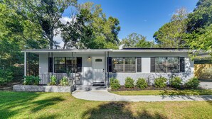 A single-story house with a front porch, a stone foundation, and a well-maintained lawn. - Emerald Coast Home: Outdoor Entertainment Area! (Mary Esther)
