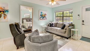 A living room with a sofa, armchair, and a ceiling fan. - Emerald Coast Home: Outdoor Entertainment Area! (Mary Esther)