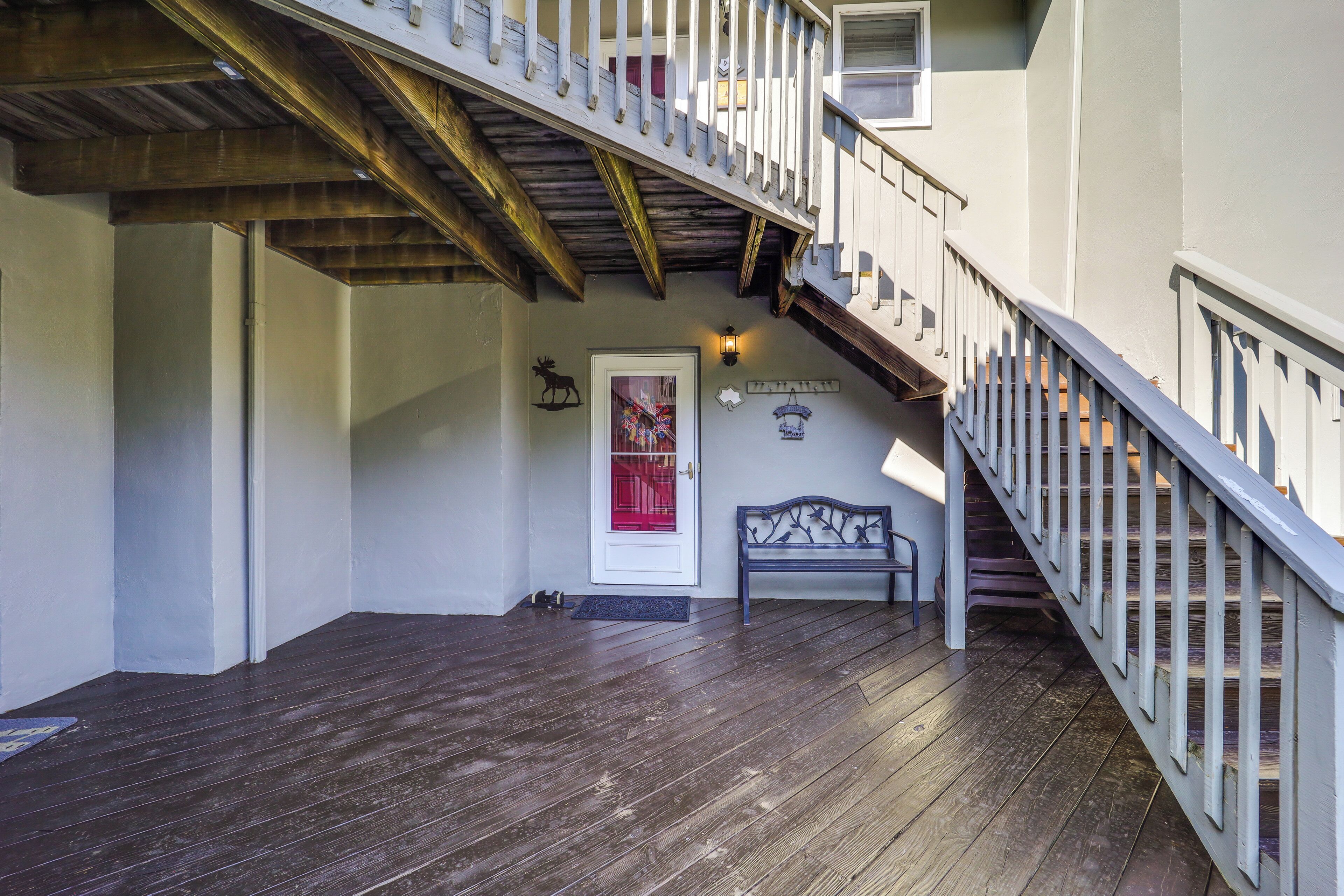 A wooden staircase leading to an upper floor, a bench, and a door with a red frame.