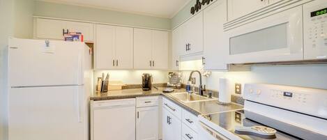 A modern kitchen with white cabinets, a built-in microwave, and an oven.