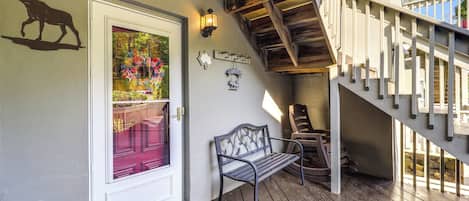 A wooden deck with a bench, a staircase, and a door with a moose silhouette.