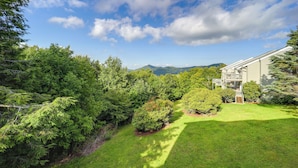 A residential property with a well-maintained lawn, a wooden deck, and a mountain backdrop. - 1 Mi to Ski Lifts: Sugar Mountain Condo (Banner Elk)