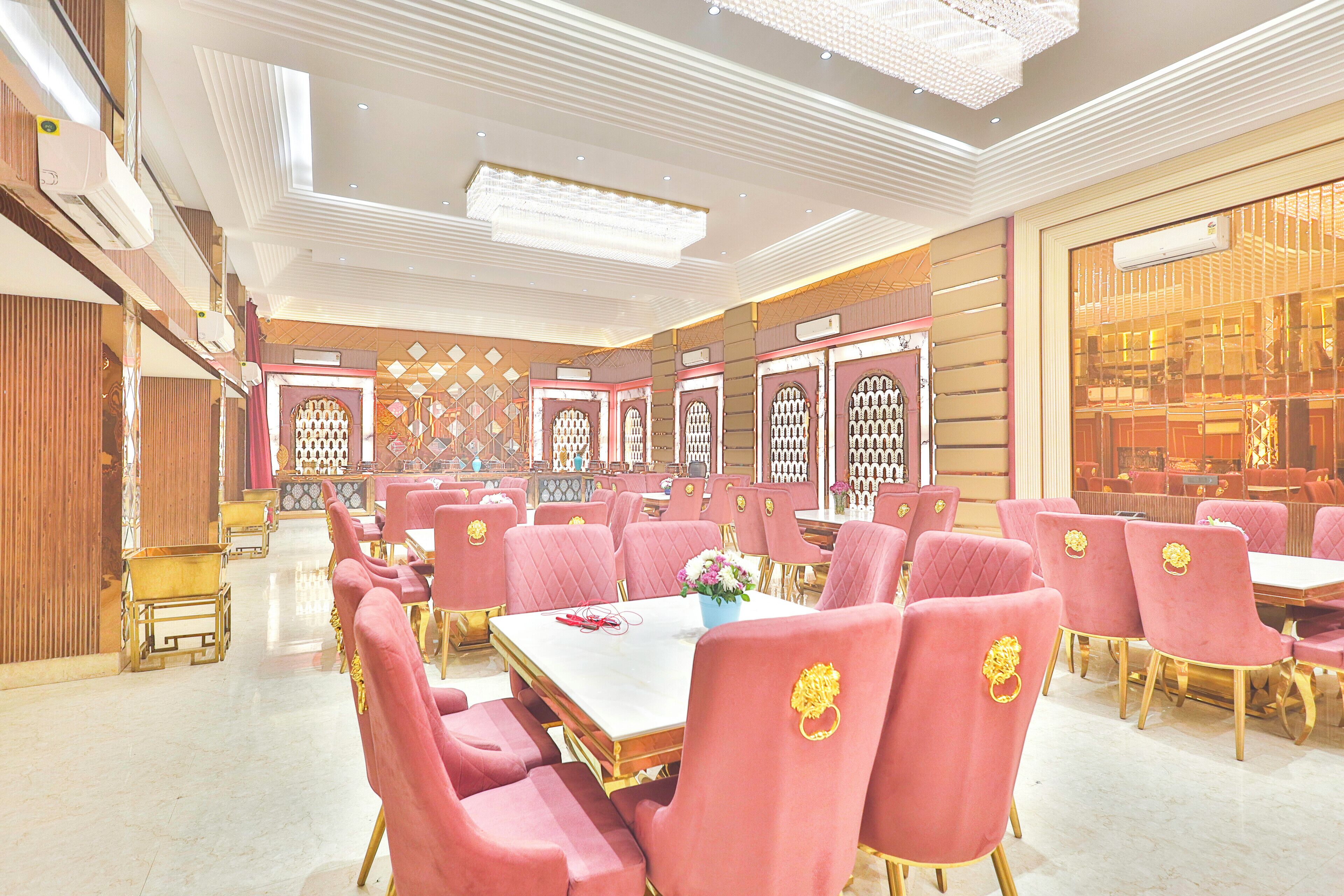 A spacious banquet hall with rows of tables and chairs, featuring a modern chandelier and decorative wall panels.