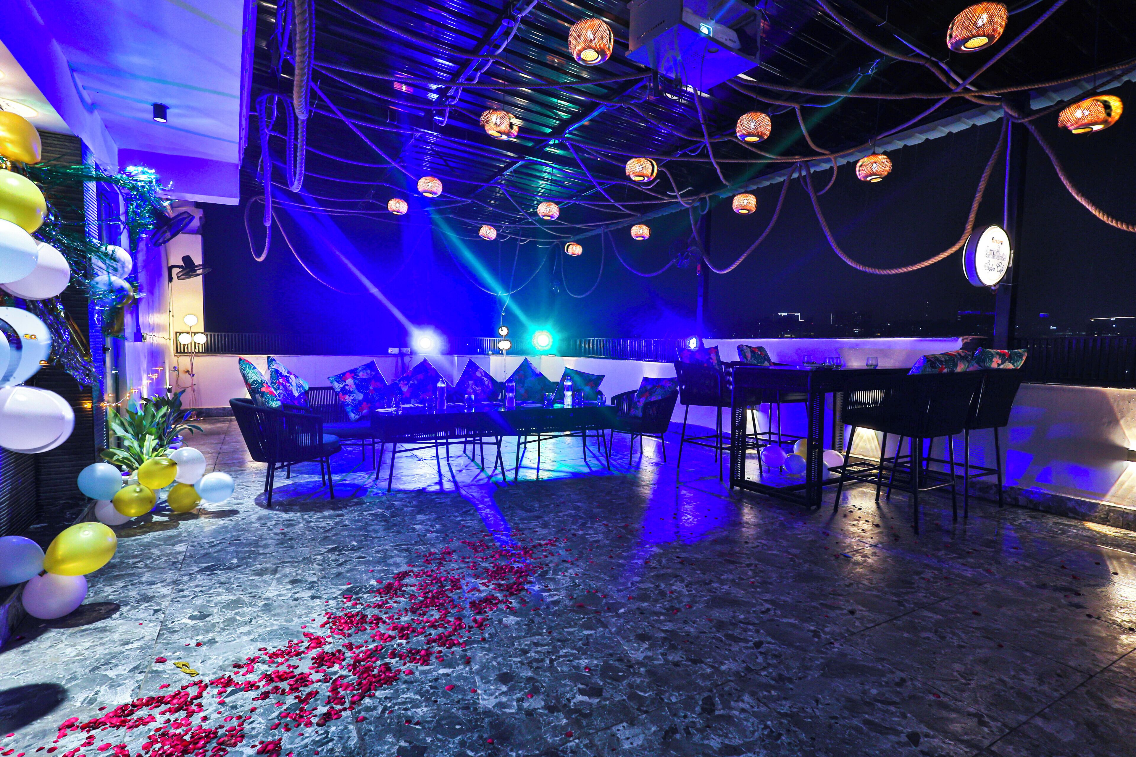 A bar area with a bar counter, chairs, and a ceiling with hanging lights.