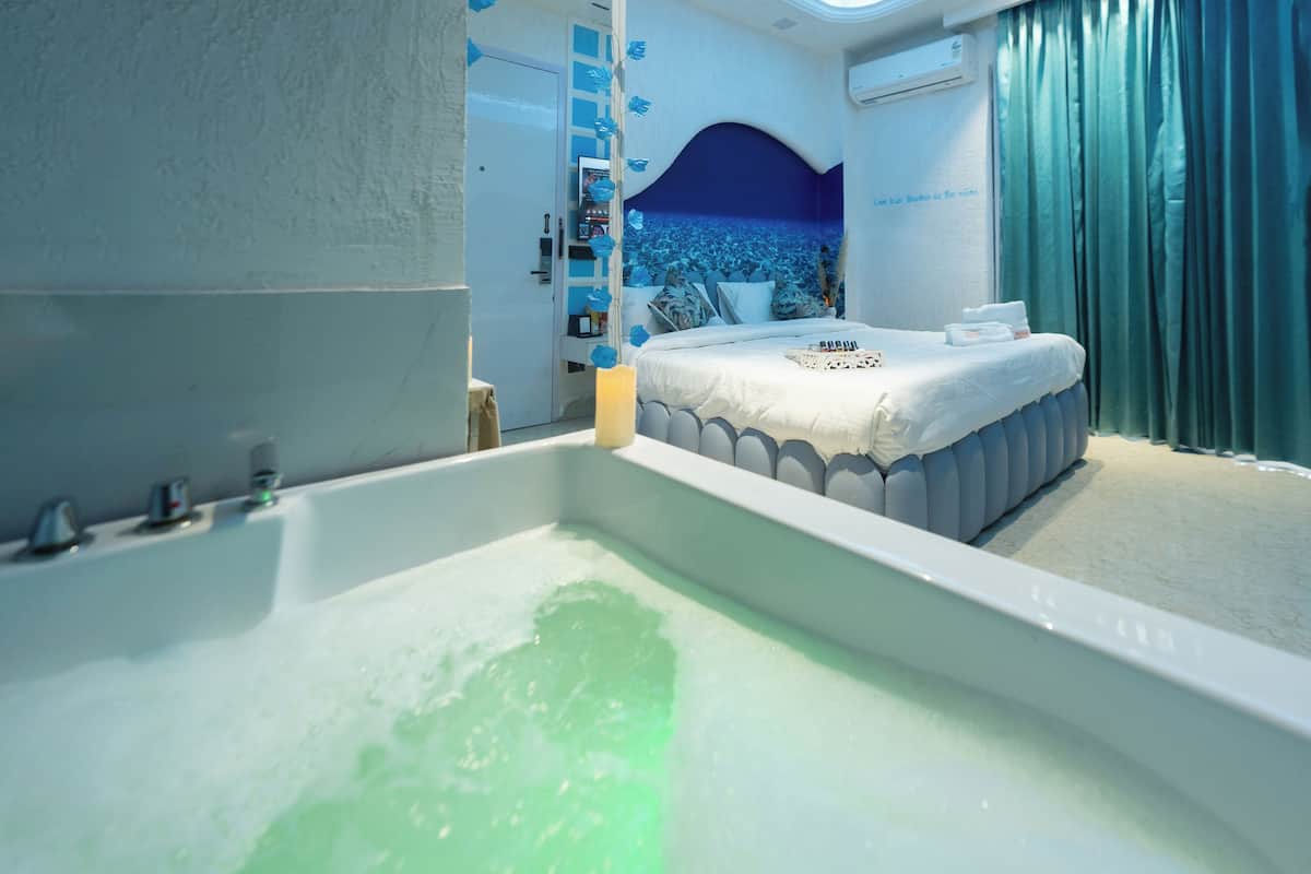 Une salle de bain moderne dotée d’une grande baignoire, d’un lit avec vue sur la mer et d’une décoration aux couleurs bleu et blanc.