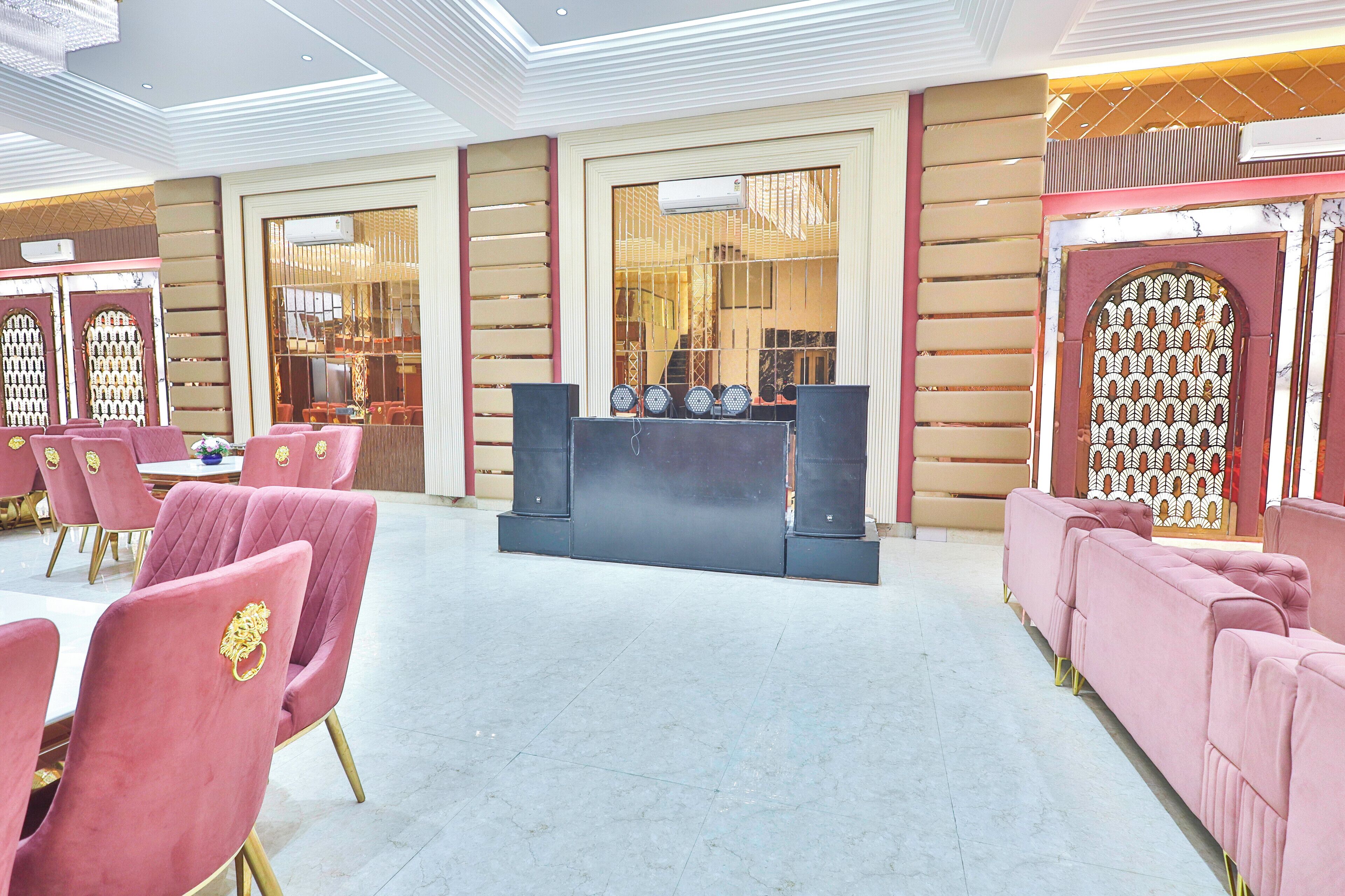 Eine Hotellobby mit einer Sitzecke, ausgestattet mit rosafarbenen Stühlen und einem schwarzen Empfangsschalter.