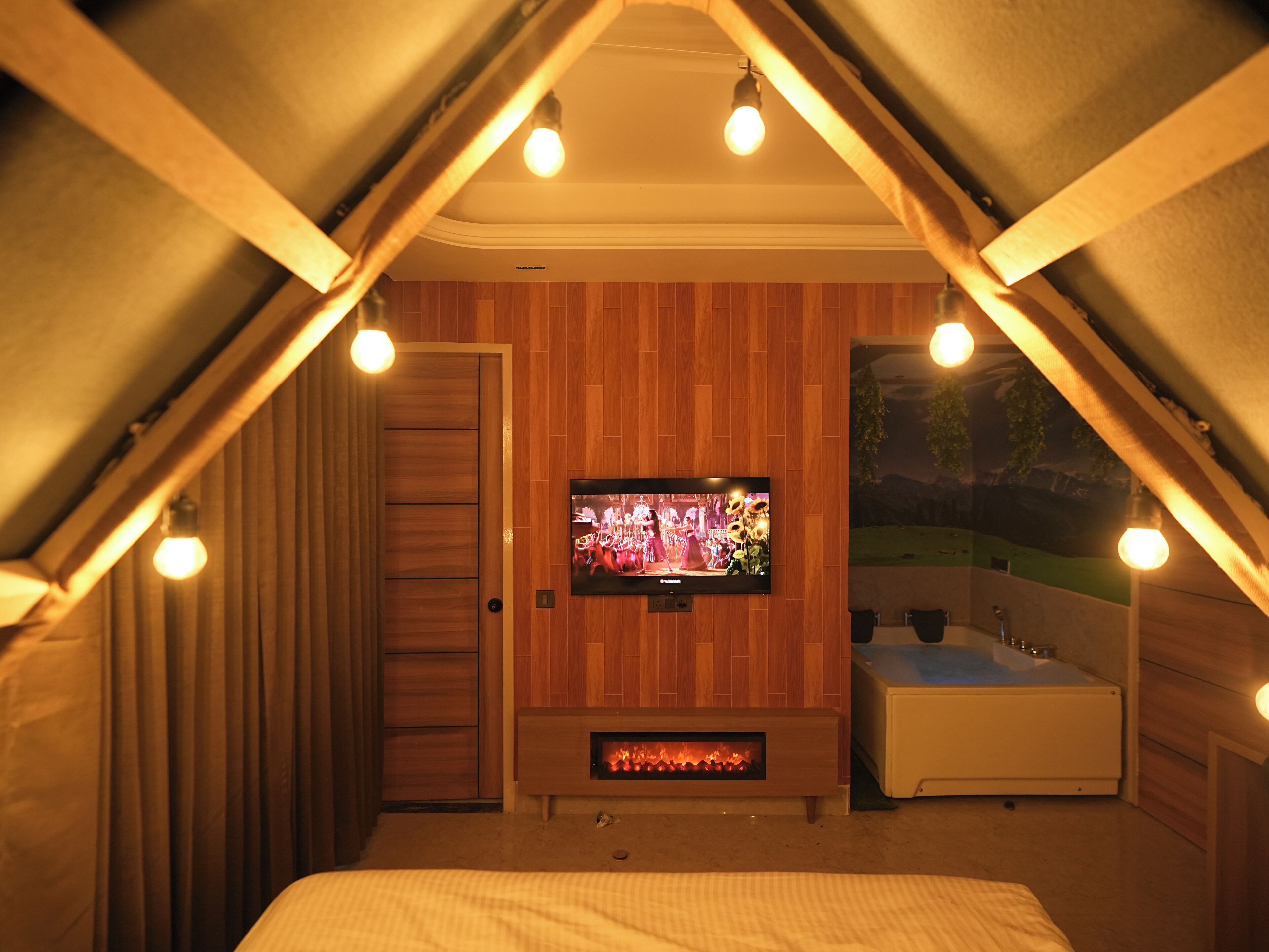 Ein gemütliches Schlafzimmer im Dachgeschoss mit Fernseher, Kamin und Badewanne.