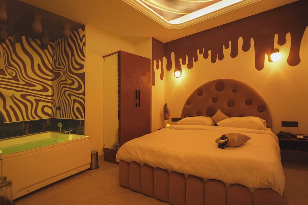 Une chambre d’hôtel moderne dotée d’un grand lit, d’une baignoire et d’un décor mural original.
