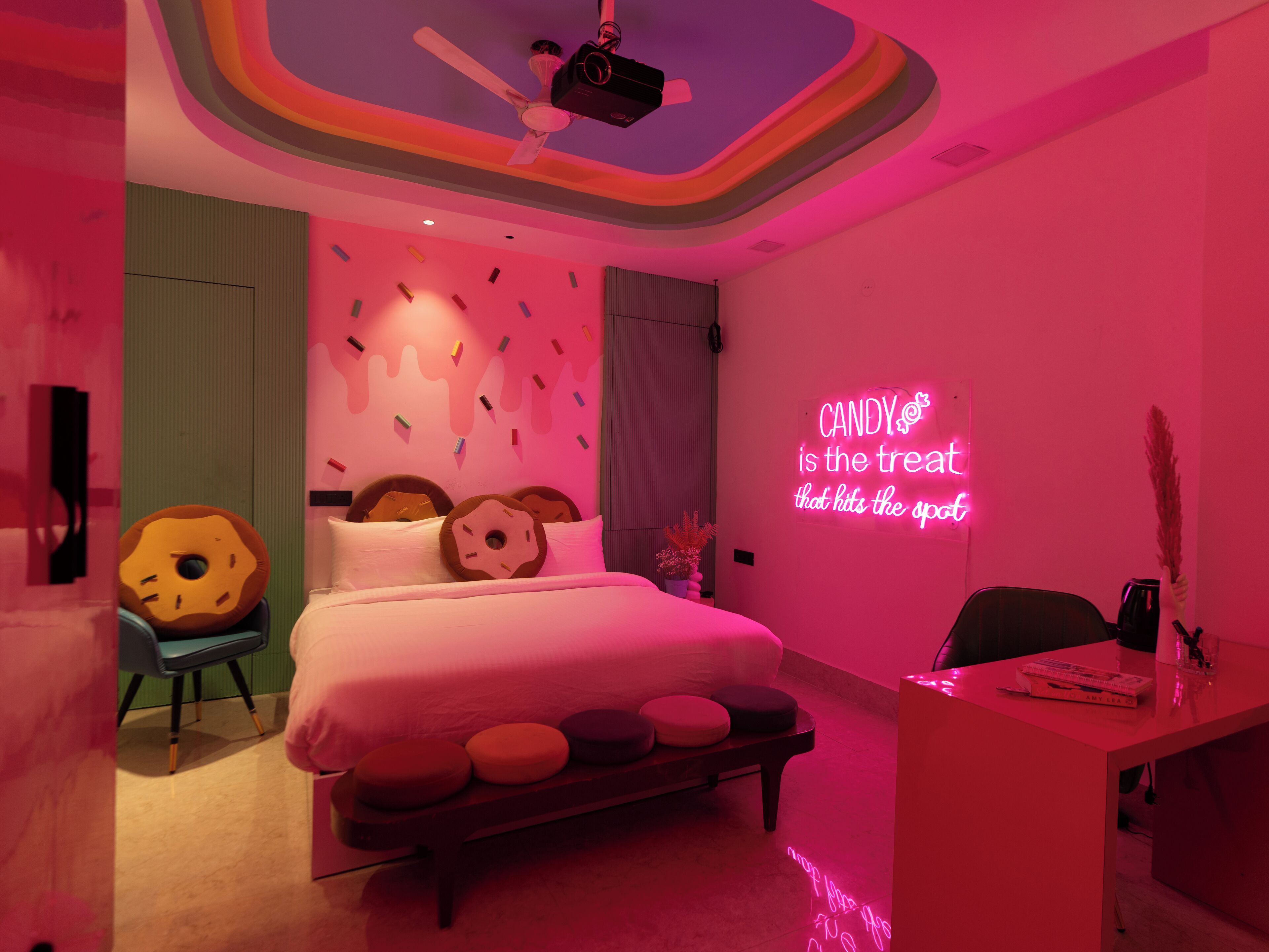 Une chambre avec un lit, un bureau et un néon mural.