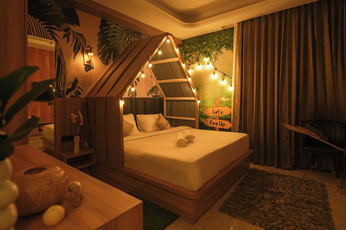 Une chambre confortable avec un lit placé sous un plafond en pente, un petit bureau et une étagère fixée au mur.