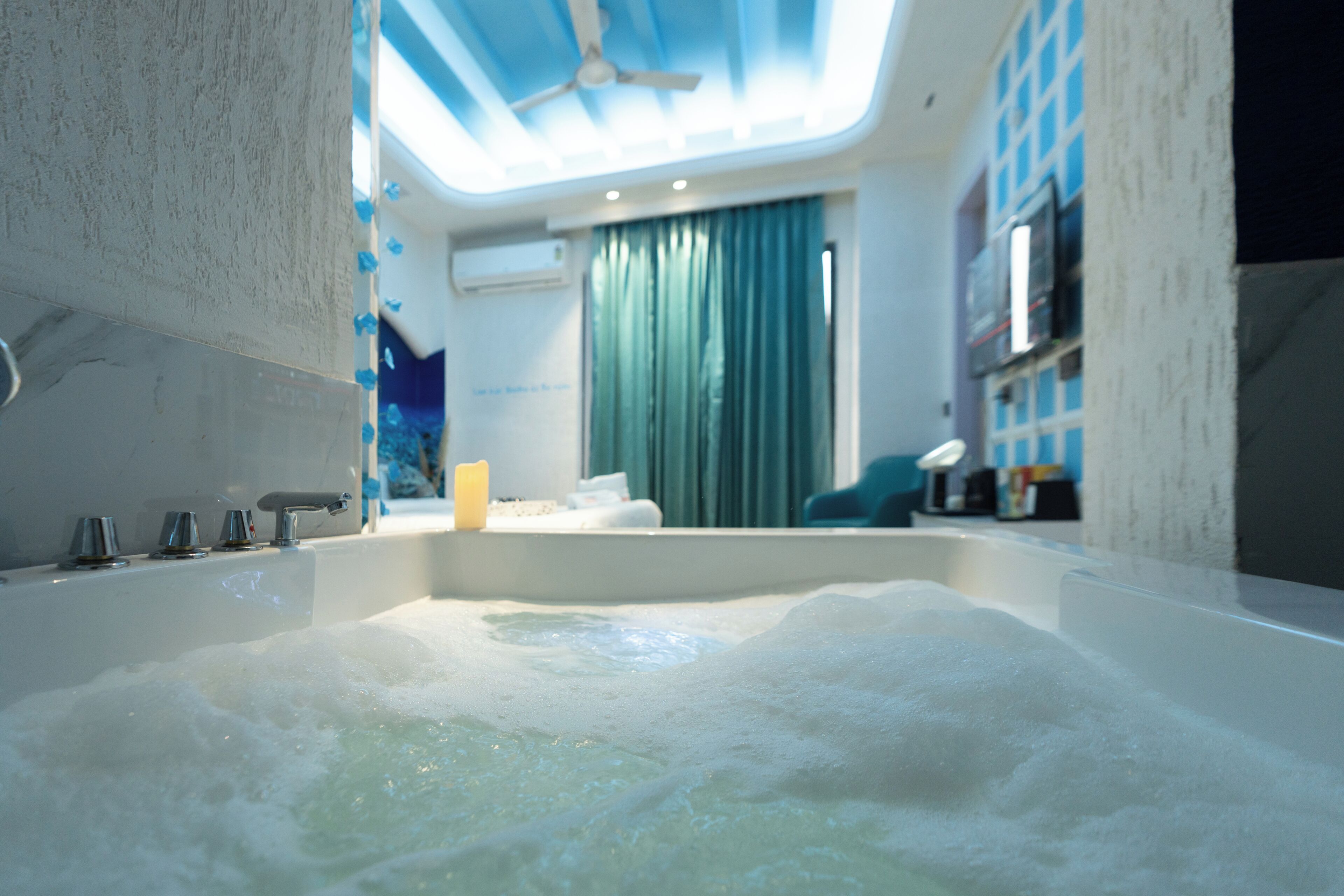 Une salle de bain moderne avec une baignoire, un ventilateur de plafond et une fenêtre avec des rideaux.