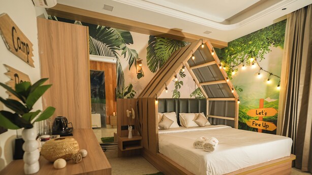 A bedroom with a wooden bed frame, a desk, and a wall mural. - Orsom Stays Sassy Sector 53 (Gurugram)