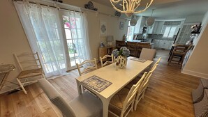 Un comedor con una mesa de madera, sillas blancas y un banco.