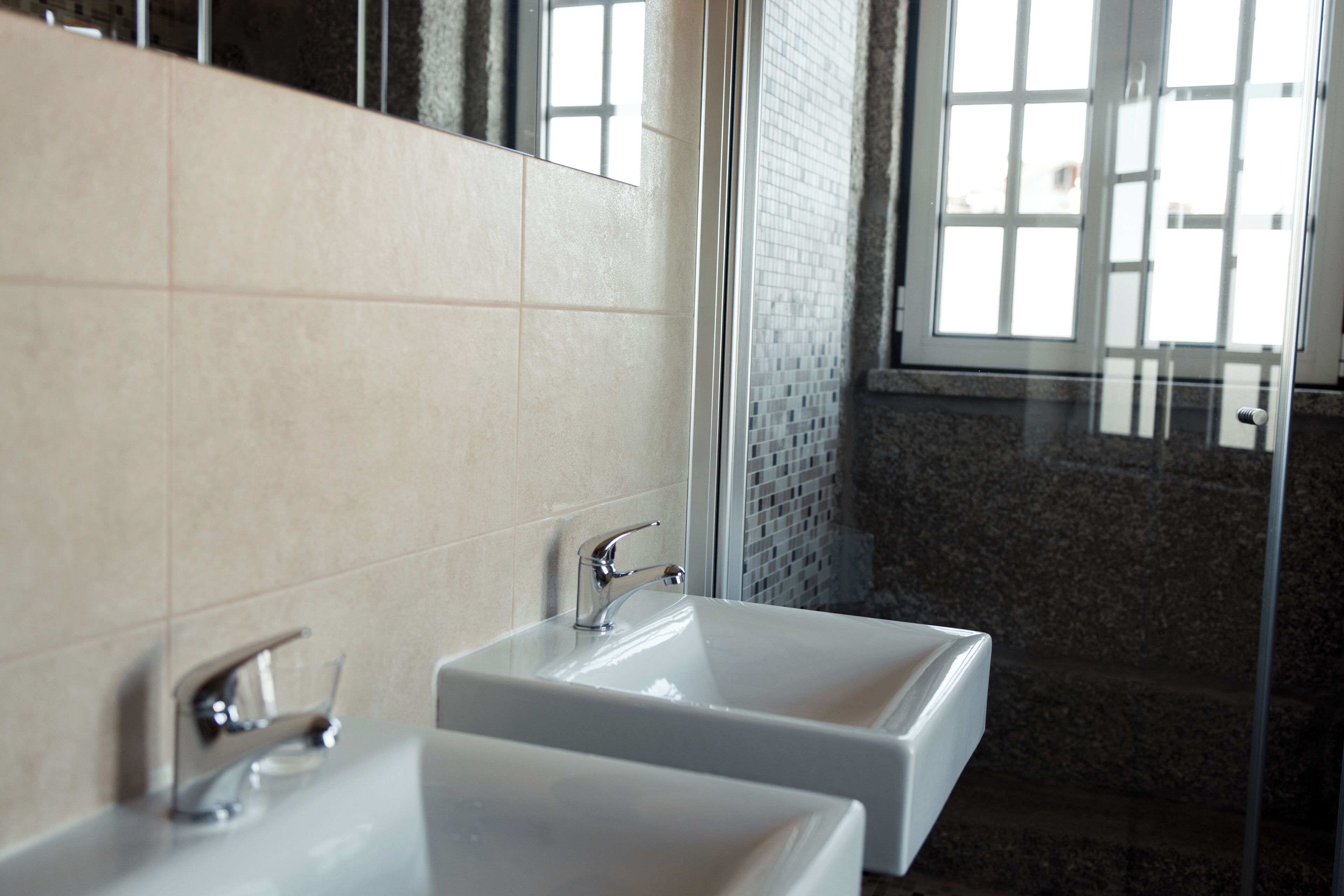 Une salle de bain avec deux lavabos, un miroir et un espace douche.