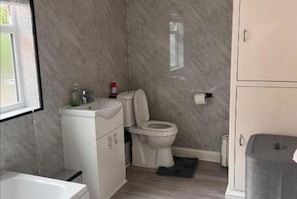 Une salle de bain équipée de toilettes, d’un lavabo et d’une baignoire.