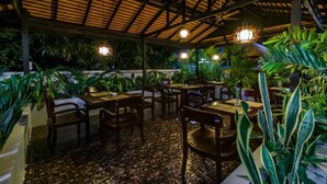 An outdoor restaurant with wooden tables and chairs, surrounded by lush greenery and a tiled floor. - Angkor Lany Sinit Resort (Siem Reap)