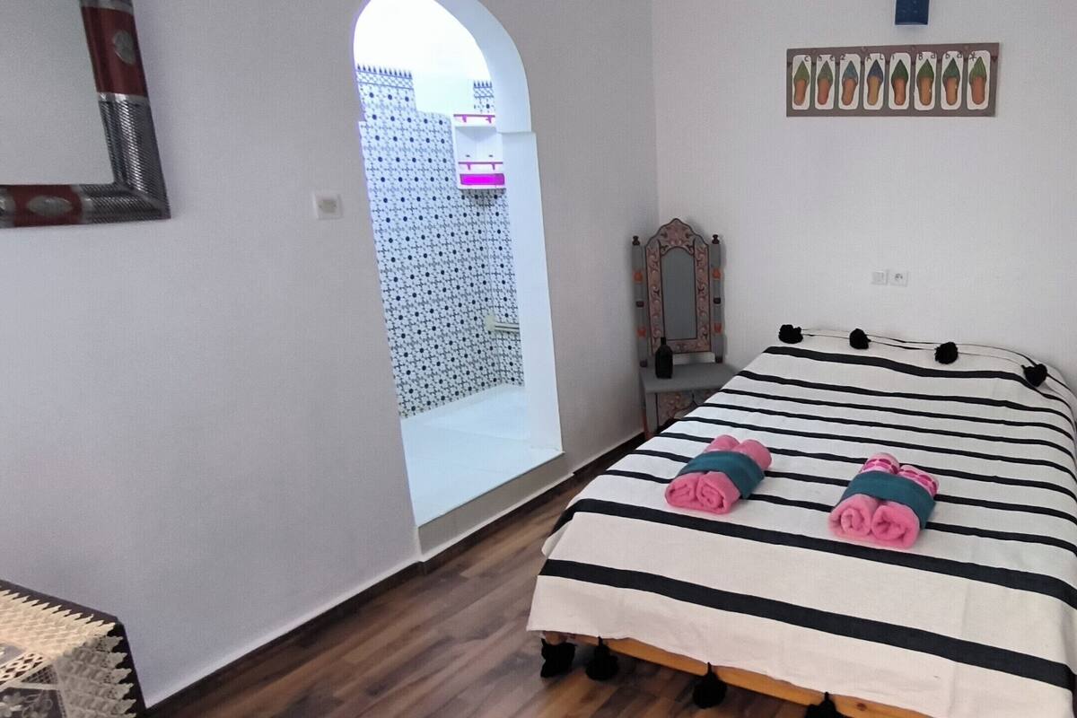 A bedroom with a bed, a mirror, and a door.