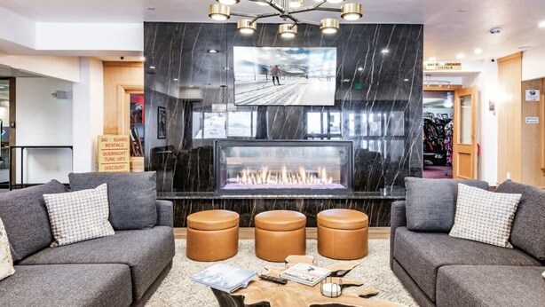 A modern lobby with a fireplace, leather sofas, a coffee table, and a large TV screen. - Ski In Ski Out 2BR Condo with Hot Tub and Pool (Park City)
