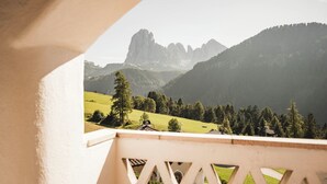 Een balkon met uitzicht op een bergachtig landschap, inclusief een opvallende bergtop en een bebost dal.