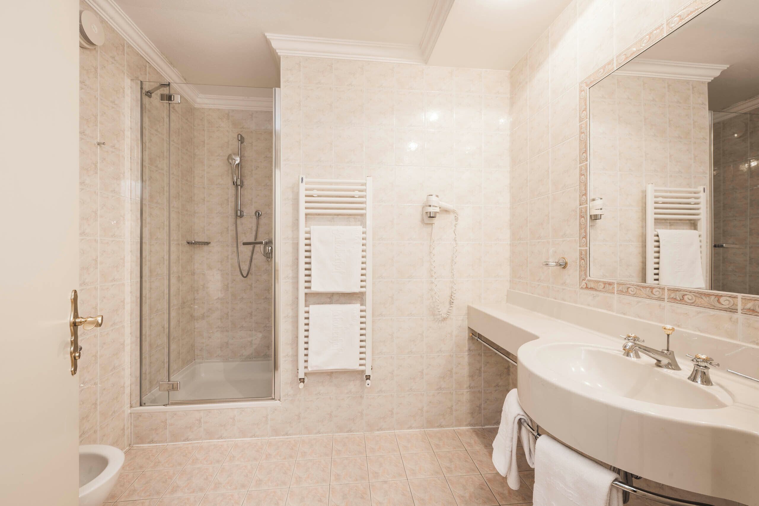 Un baño moderno con ducha envuelta en vidrio, un lavamanos espacioso y un espejo.