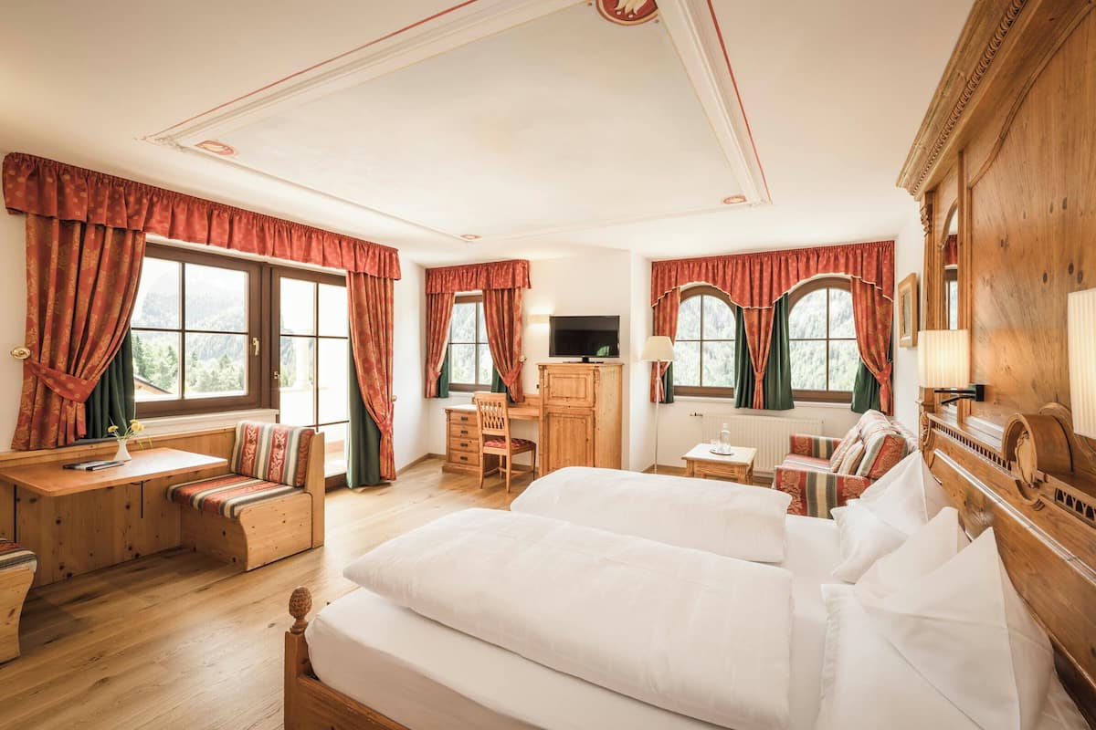 Un dormitorio acogedor con una cama grande, un escritorio de madera, una silla y un televisor.