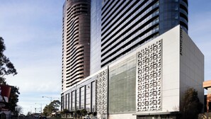 A modern building with a cylindrical tower and a rectangular section with a geometric facade.
