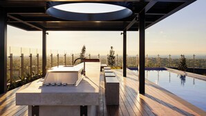 A modern outdoor bathroom with a freestanding tub, a large window, and a view of a cityscape.