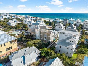 Un quartier résidentiel situé sur la côte, composé de nombreuses maisons à deux étages, dont certaines sont dotées de balcons, et offrant une vue sur l’océan.