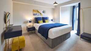 Un dormitorio moderno con una cama grande, mesitas de noche, un escritorio y una silla.