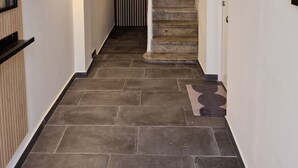 A hallway with a staircase leading to a door, tiled flooring, and wall-mounted light fixtures. - Spacious, modern apartment located just outside the historic center. (Málaga)