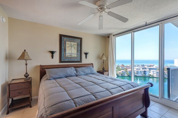 Relax in a serene coastal retreat with a large bed, ceiling fan, and stunning ocean views.