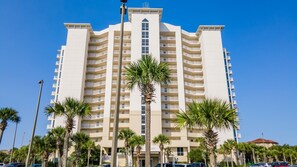 Guests can enjoy stunning views from the multiple balconies of this high-rise hotel, surrounded by lush palm trees.