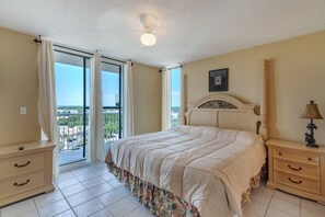 Relax in a spacious room with a large bed, balcony, and nightstand featuring a lamp and decorative statue.