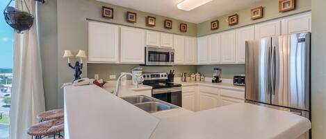 A modern kitchen with white cabinets, stainless steel appliances, and a large island.