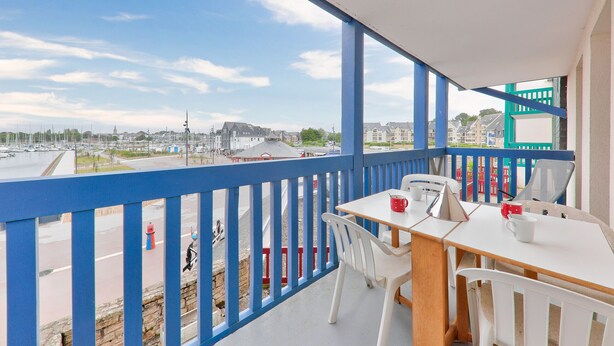 A balcony with a white table and chairs, a red mug, and a view of a marina and buildings. - Crouesty Harbor, flat with a pool for 4 (Arzon)