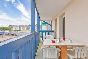 A balcony with a white table and chairs, a red mug, and a white mug. - Crouesty Harbor, flat with a pool for 4 (Arzon)