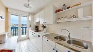 A modern kitchen with white cabinets, stainless steel sinks, and a view through the glass doors. - Crouesty Harbor, flat with a pool for 4 (Arzon)