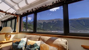 A room with a leather sofa, decorative pillows, a lamp, and large windows offering a mountain view. - Vs741 Village Sqaure 3 Bedroom Condo by RedAwning (Copper Mountain)