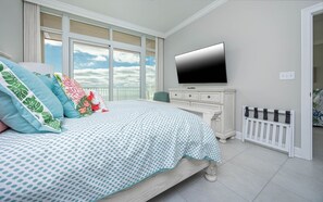 Ein Schlafzimmer mit Bett, Fernseher, Kommode und einem Fenster mit Blick auf den Himmel.
