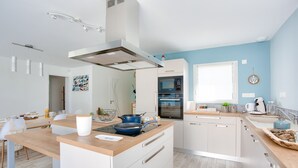 A modern kitchen with white cabinets, a wooden countertop, and a built-in oven. - Modern house with garden - 5min from the beach (Erquy)