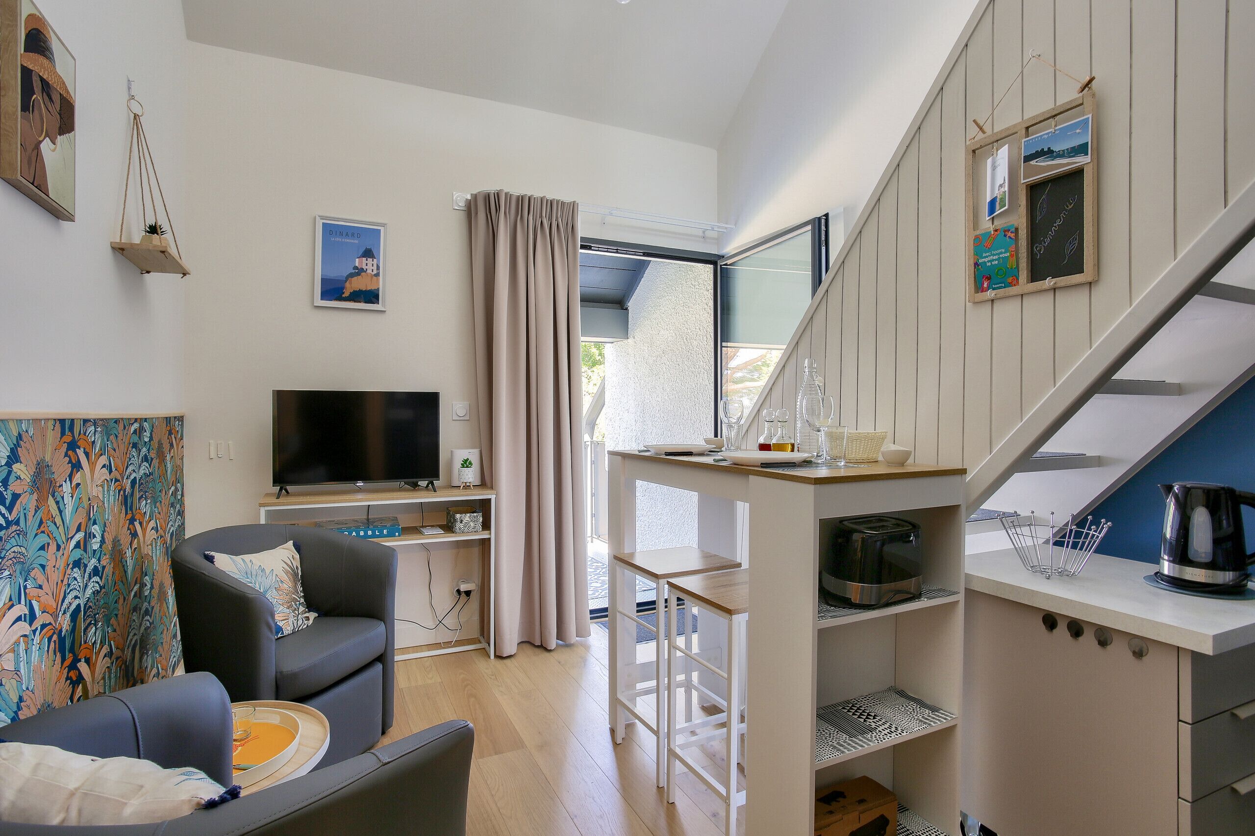 A modern living room with a flat-screen TV, a sofa, a coffee table, and a dining area with a table and chairs.
