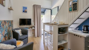En moderne stue med et fladskærms-tv, en sofa, et sofabord og et spiseområde med bord og stole.