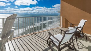 A balcony with a view of the ocean, featuring two white chairs and a table. - Phoenix Gulf Towers 2707 3 Bedroom Condo by RedAwning (Orange Beach)