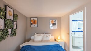 A bedroom with a bed, bedside table, and wall art. - Luminous Suite In Brussels - Elegant Design (Bruxelles)