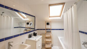 A modern bathroom with a skylight, a bathtub, a shower, and a vanity with a mirror. - Luminous Suite In Brussels - Elegant Design (Bruxelles)