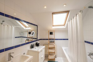 Un baño moderno con tragaluz, bañera, ducha y tocador con espejo.